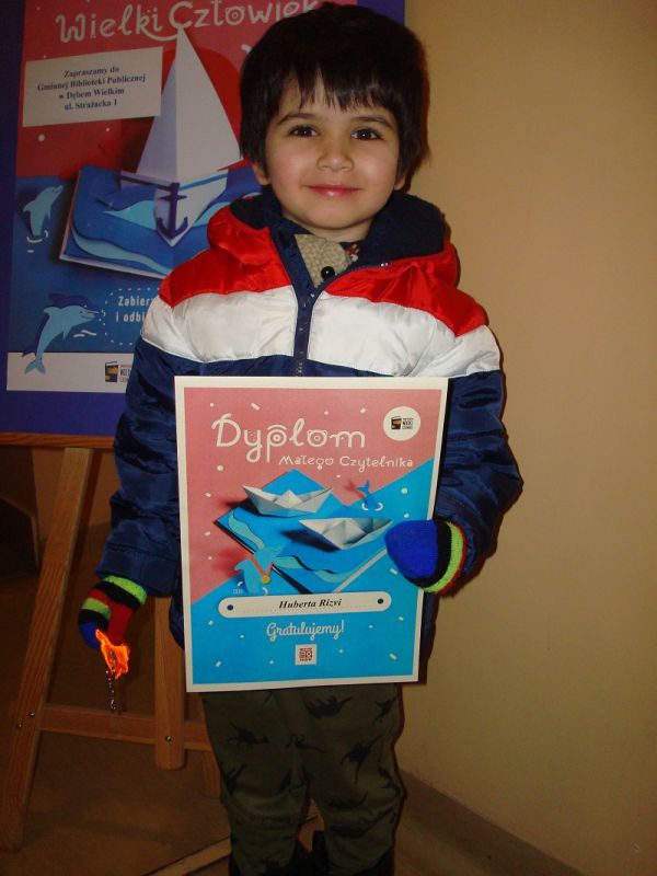 Zdjęcie przedstawia chłopca trzymającego w rękach Dyplom Małego Czytelnika